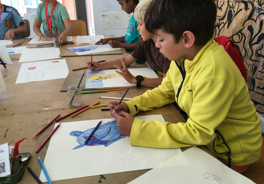 Des enfants assis à une table en train de dessiner avec des crayons de couleur.